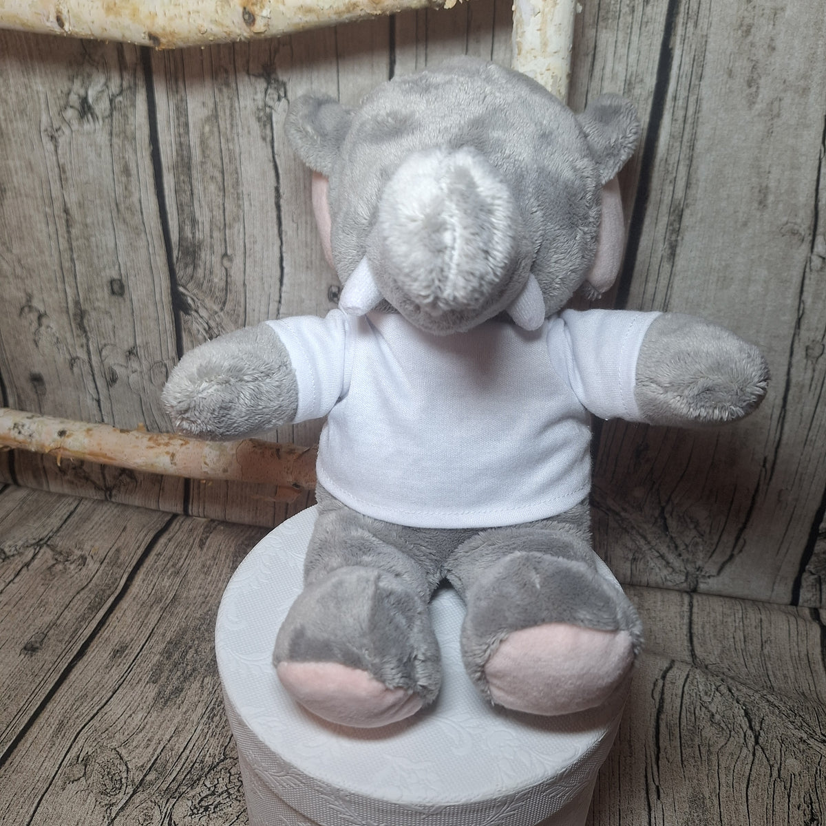 Grauer Plüschelefant mit rosa Details und weißem, unbedrucktem T-Shirt in Vorderansicht.