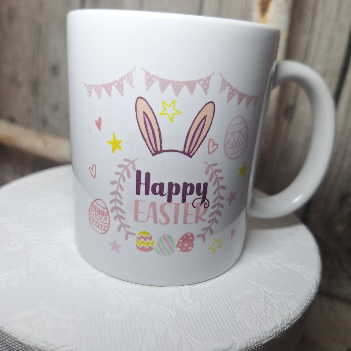 Ostertasse in leicht gedrehter Ansicht mit „Happy Easter“, rosa Hasenohren und bunten Ostereiern.
