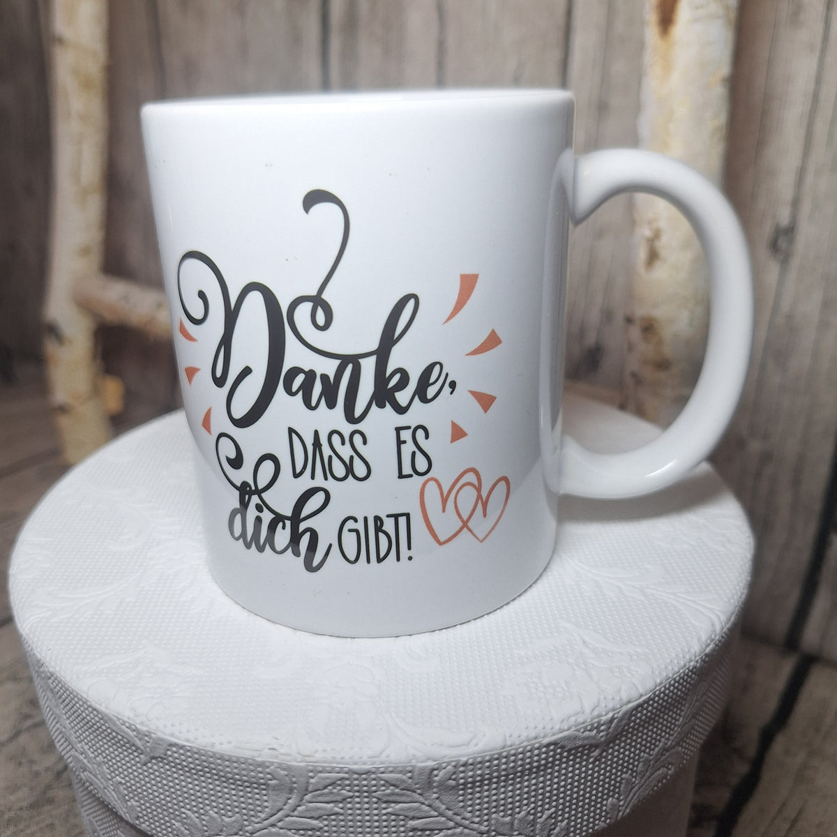 Weiße Keramiktasse mit dem Schriftzug „Danke, dass es dich gibt!“ und lachsfarbenen Herzen, Henkel rechts.
