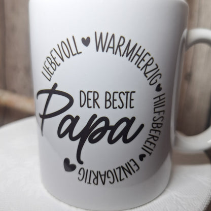 Nahaufnahme des Aufdrucks „Der beste Papa“, umrahmt von liebevoll, warmherzig, hilfsbereit und einzigartig sowie Herzen.