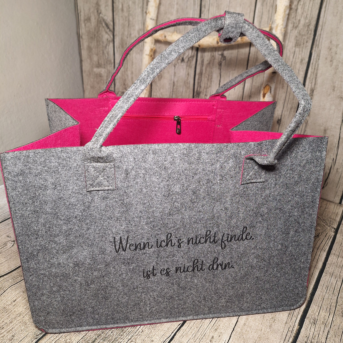Graue Filztasche mit pinker Innenseite und dem Spruch: Wenn ich’s nicht finde, ist es nicht drin.