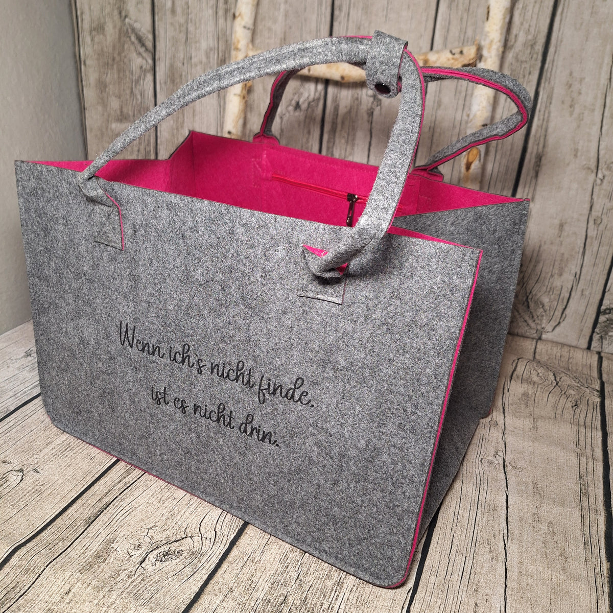 Graue Filztasche mit lustigem Spruch, pinker Innenseite und langen Tragegriffen in schräger Vorderansicht.