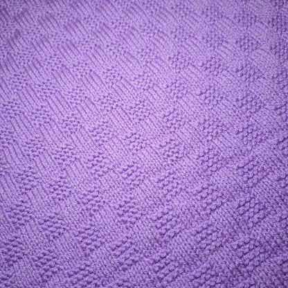 Nahaufnahme des rechteckigen Strukturmusters der handgestrickten Babydecke in Flieder.
