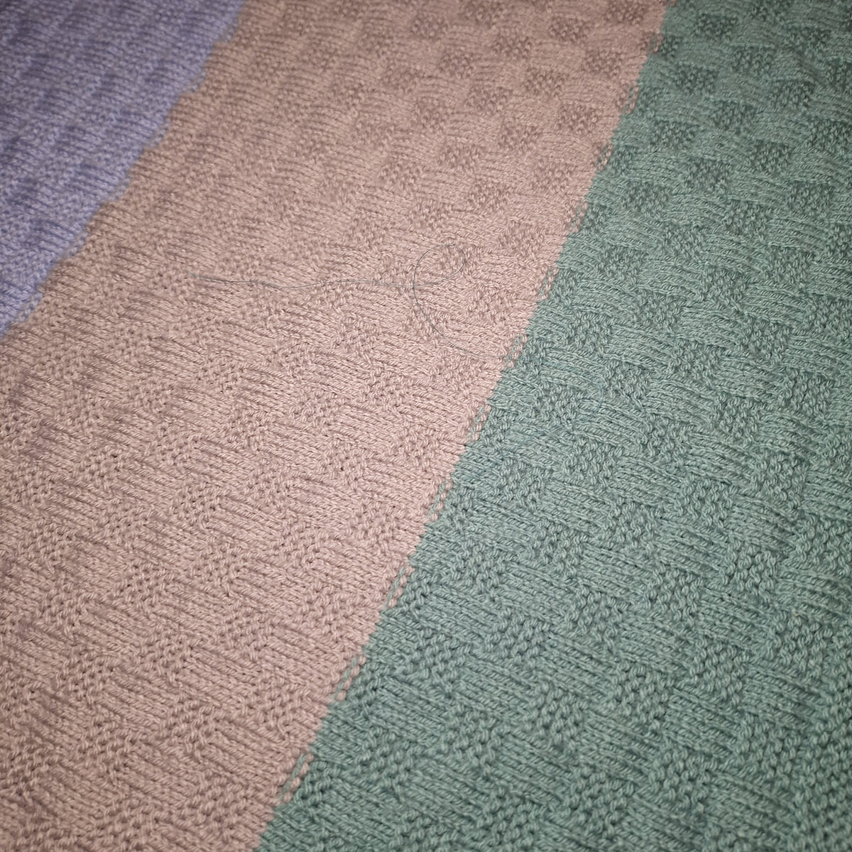 Nahaufnahme der Pastellstreifen mit rechteckigem Strickmuster und sichtbaren Farbwechseln.