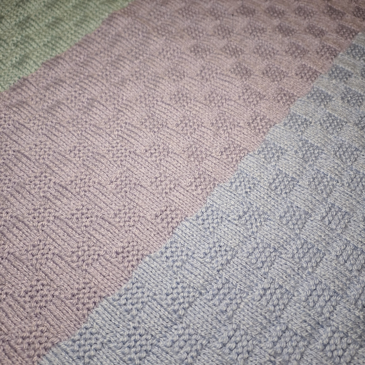 Detail der hellen Pastellstreifen und der abwechselnd glatten und erhabenen Strickflächen.
