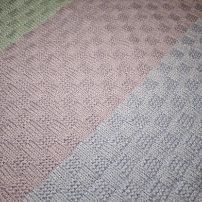 Detail der hellen Pastellstreifen und der abwechselnd glatten und erhabenen Strickflächen.